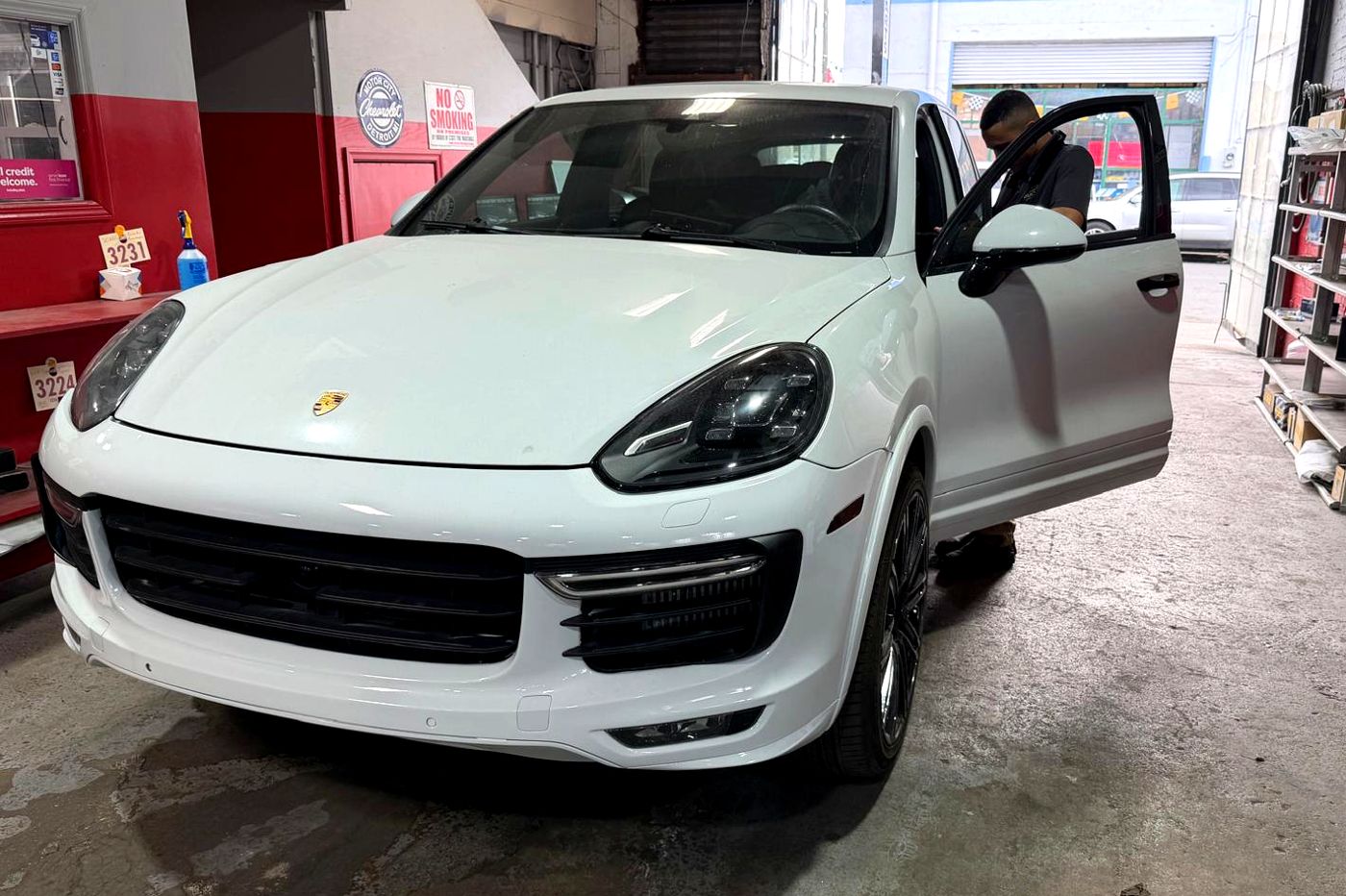White Porsche Cayenne GTS in the shop with a technician at the door