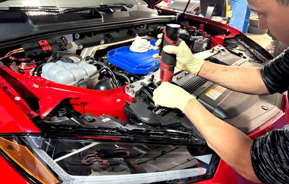 Technician working under the hood of a red car